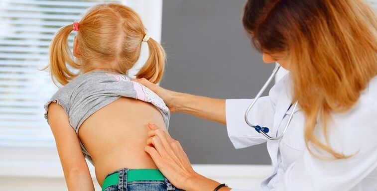 Doctor examines the back of a child with back pain